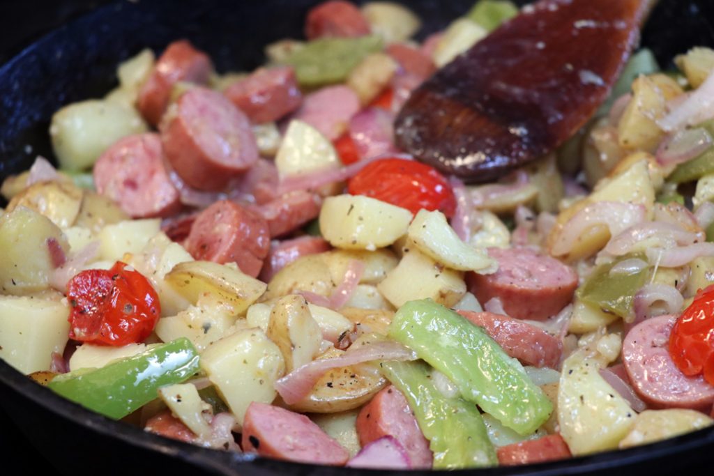 kielbasa and potato with onions and peppers in a cast iron pan