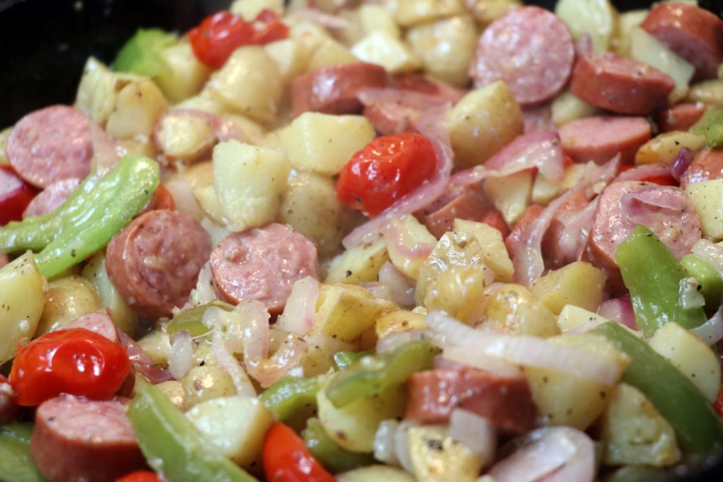 smoked sausage, peppers, onions, and potatoes in a cast iron skillet 