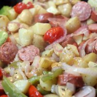 smoked sausage, peppers, onions, and potatoes in a cast iron skillet