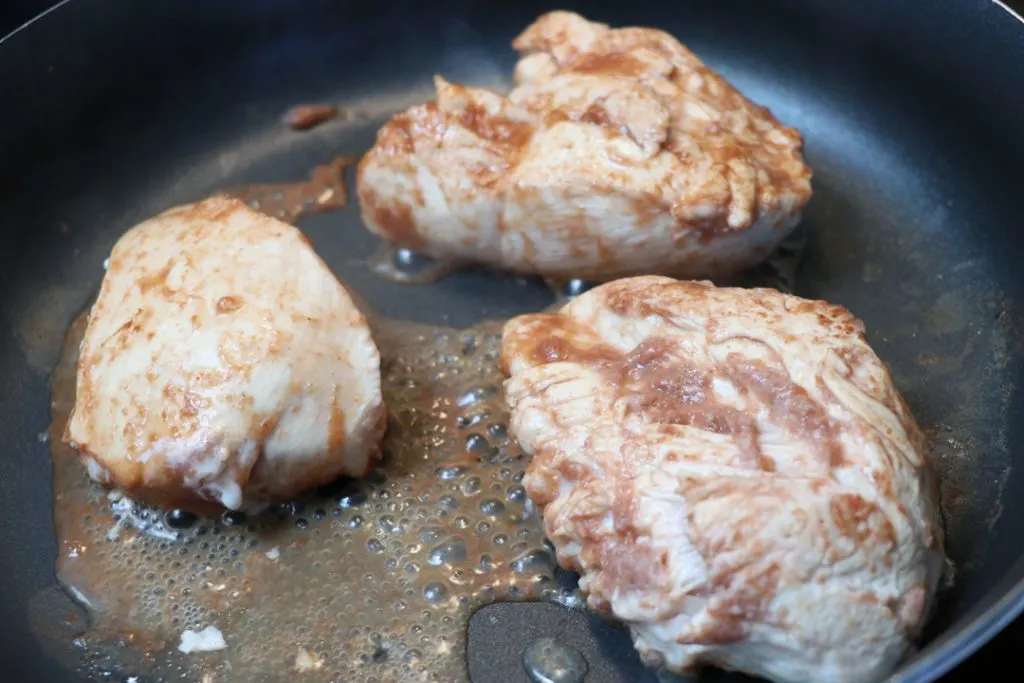 chicken breasts cooking in a skillet