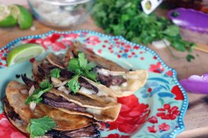 Freshly made Birria Tacos on a plate with beef and cilantro