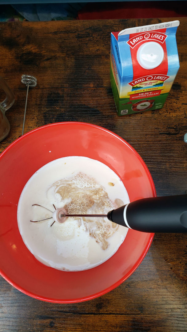 making sweet cold foam with heavy cream, vanilla, and sweetened condensed milk in a bowl with a milk frother