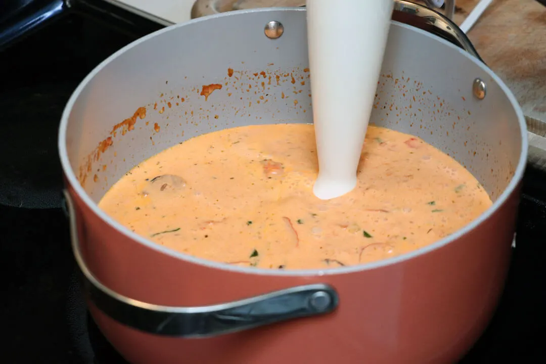 immersion blender in a Dutch oven making creamy tomato basil soup
