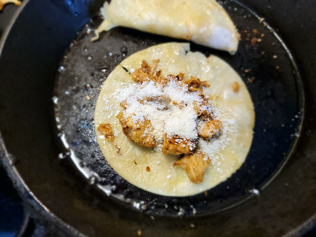 fried chicken tacos in a cast iron pan with corn tortilla and cheese