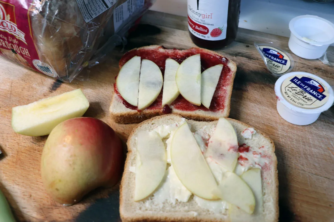 brie, raspberry jam, and apple grilled cheese on sourdough deconstructed on a cutting board