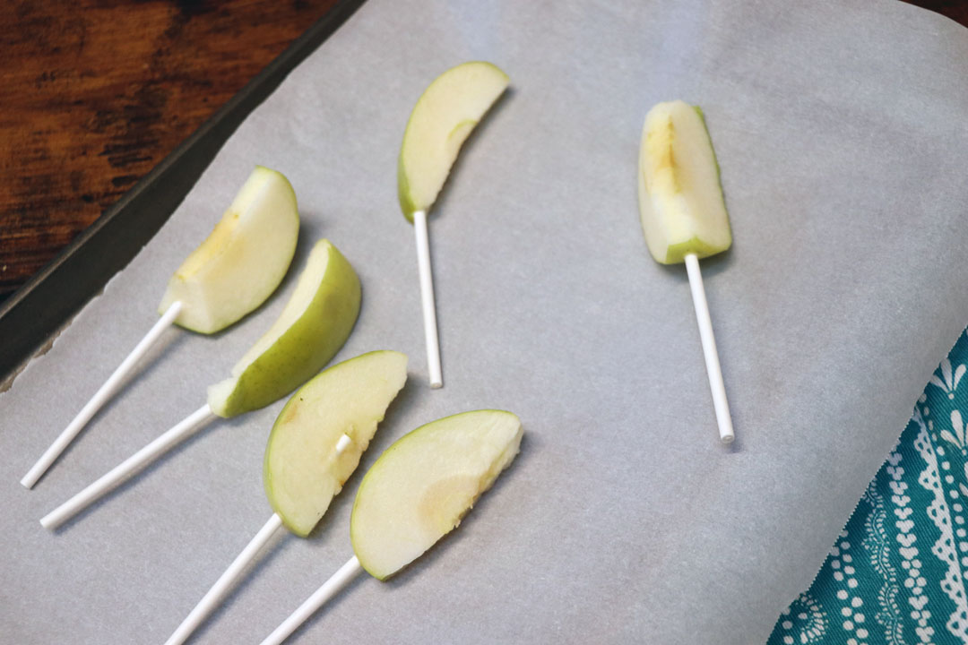 green apples slices and on a stick to make caramel apple sticks