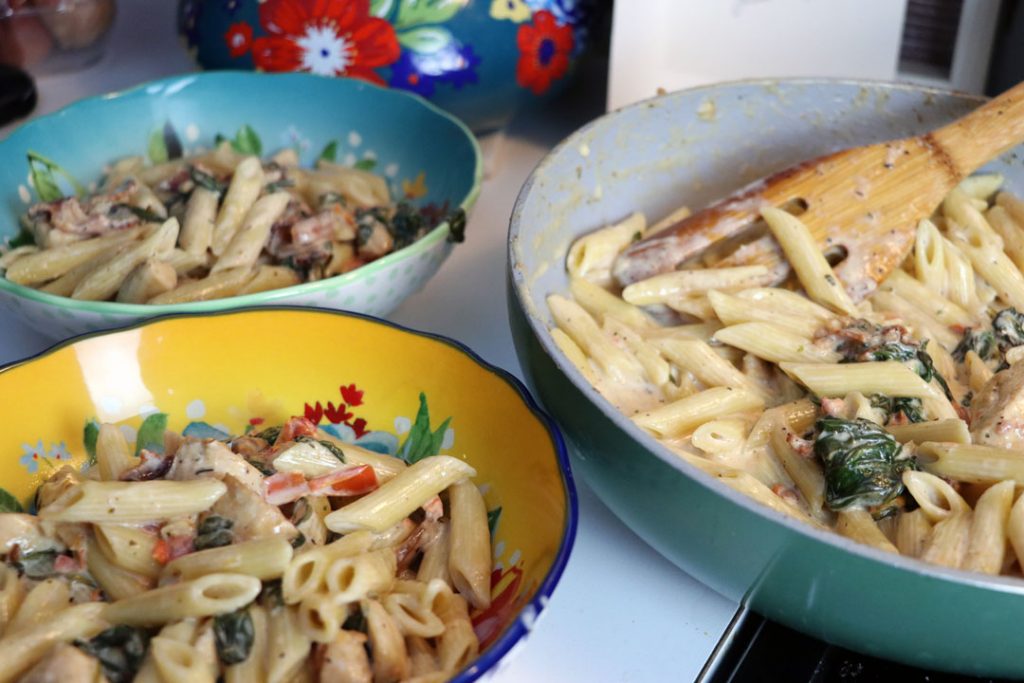 creamy penne pasta with chicken bacon and spinach in bowls