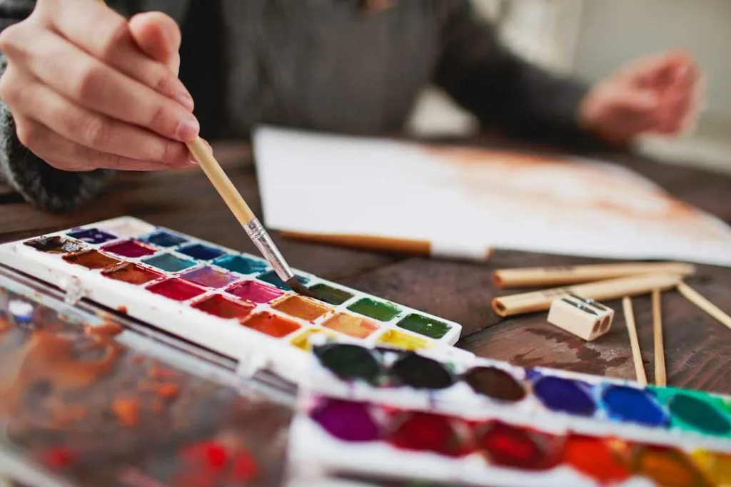 Close-up of adult hands painting with watercolors

