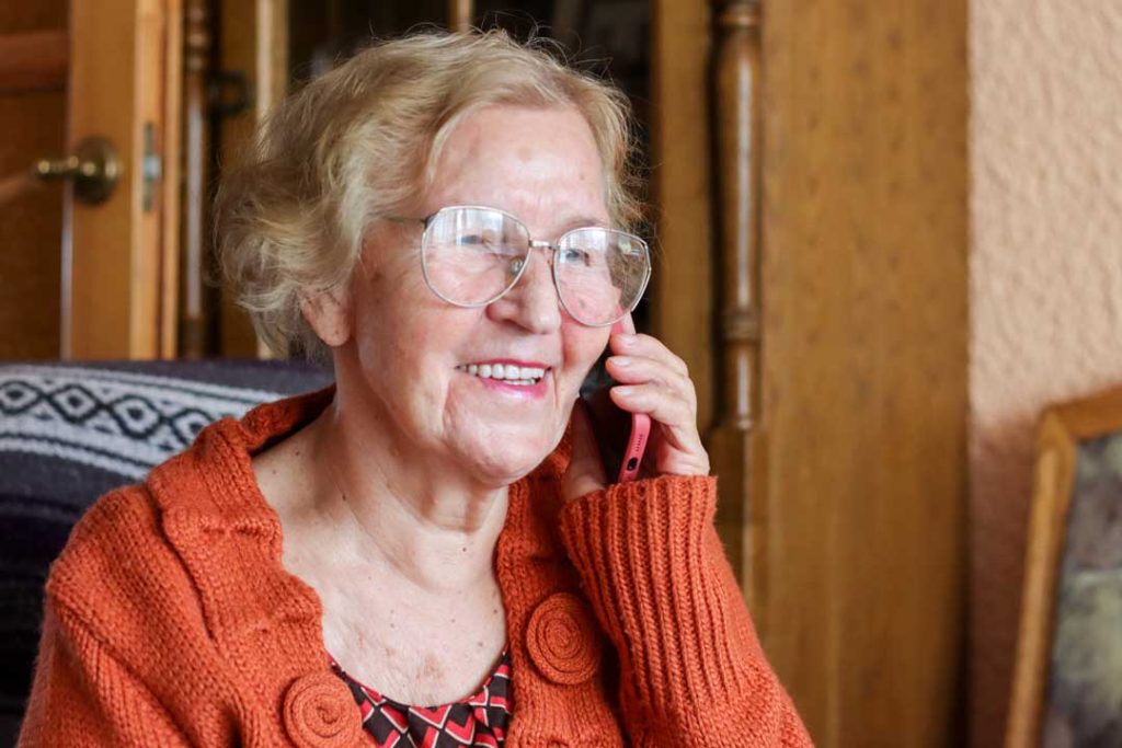 Elderly person smiling while using a personal emergency alert system