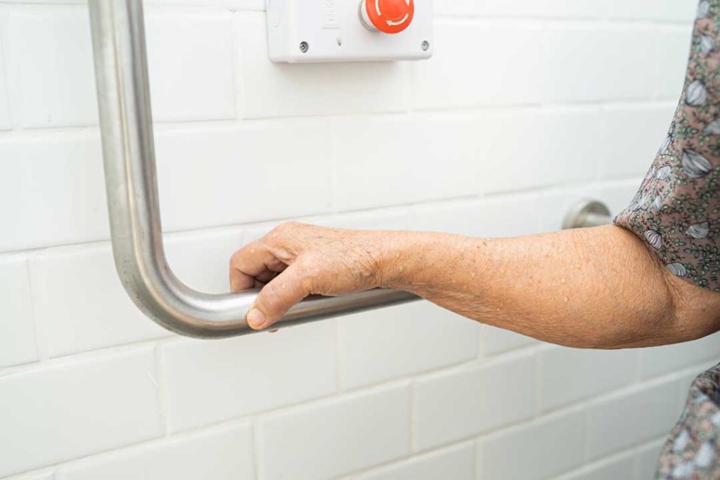 Elderly person using grab bar for bathroom safety