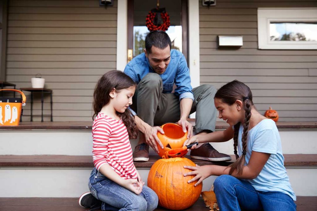Family carving pumpkins on the porch