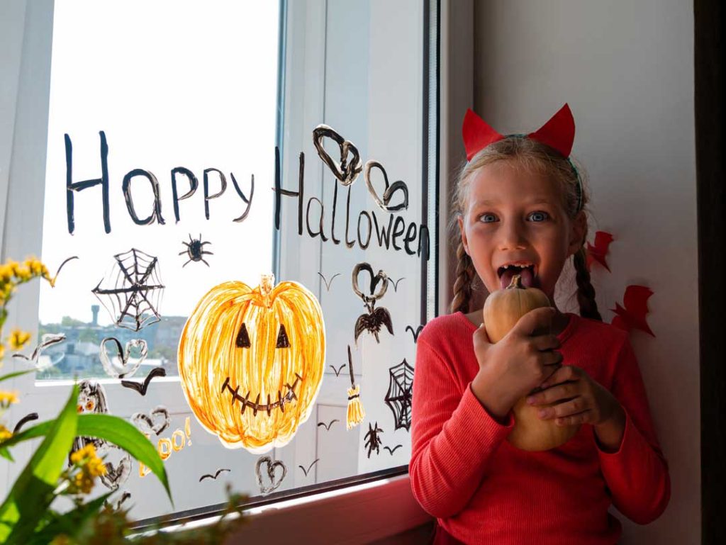 Kids placing Halloween window decorations