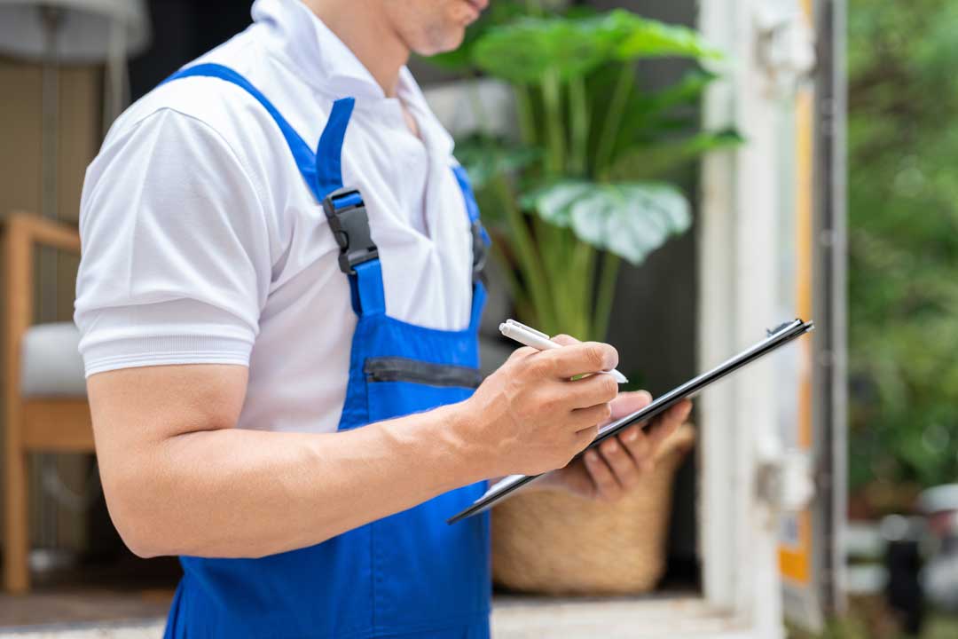 Pest control technician inspecting a home with clipboard