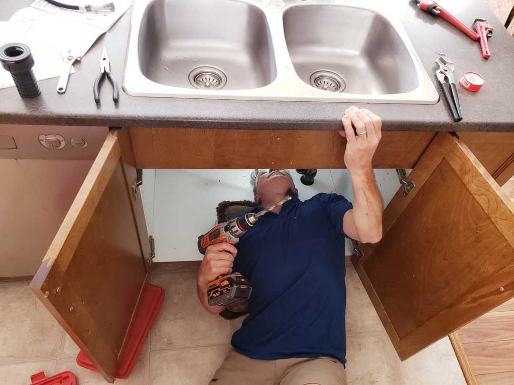 Water leak under a kitchen sink being repaired