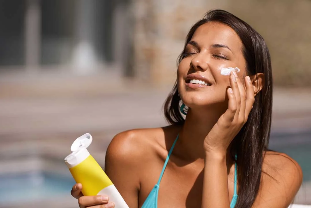Woman applying SPF sunscreen on face during sunny day