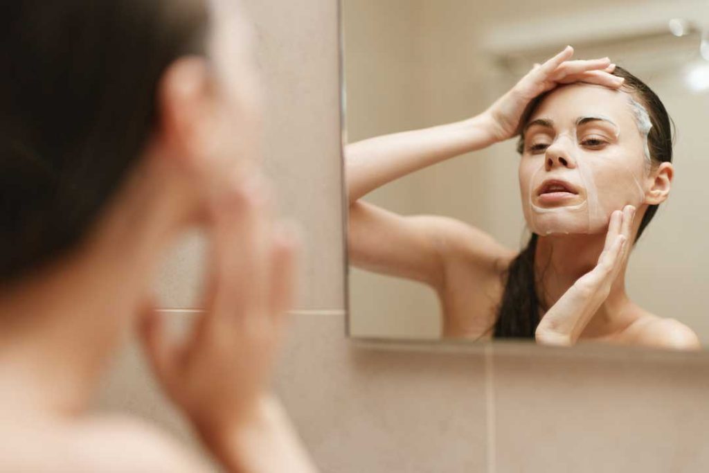 Woman looking in mirror, gently touching her face