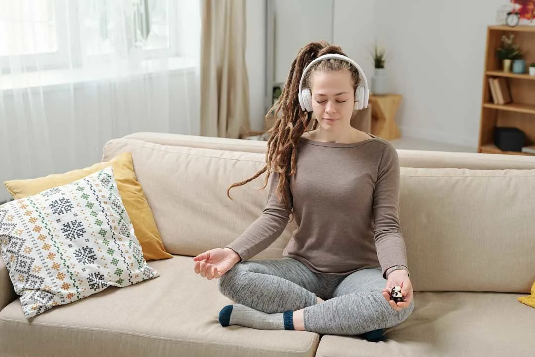 Woman meditating on couch with headphones