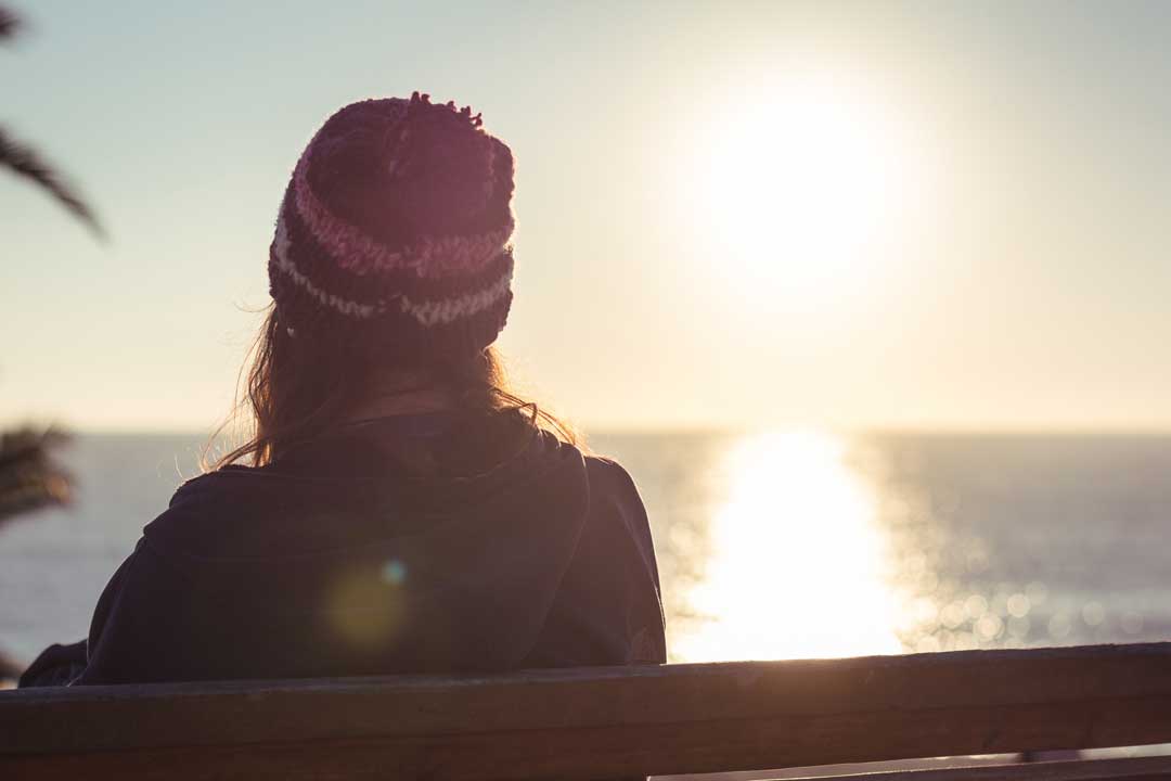 grieving person looking at sunrise over ocean, reflecting on wrongful death lawsuit benefits