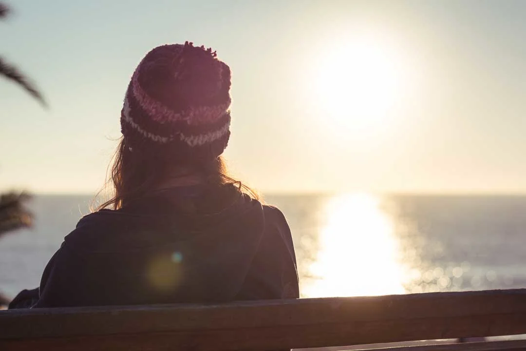 grieving person looking at sunrise over ocean, reflecting on wrongful death lawsuit benefits