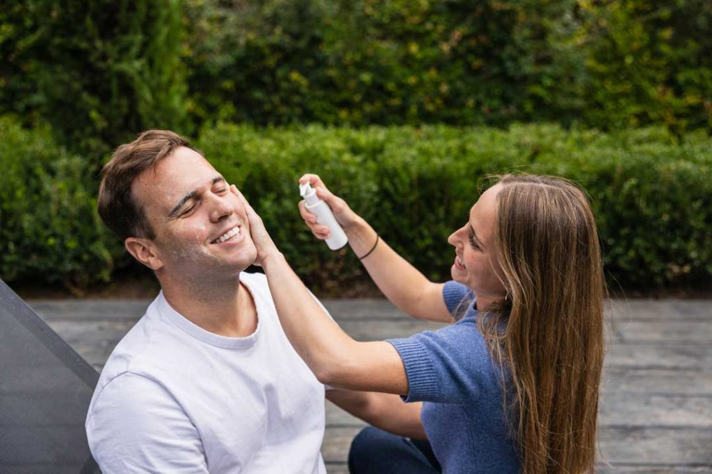 applying sunscreen to a child before a fishing trip, with bug spray and hand wipes visible nearby, stressing the importance of protection.
