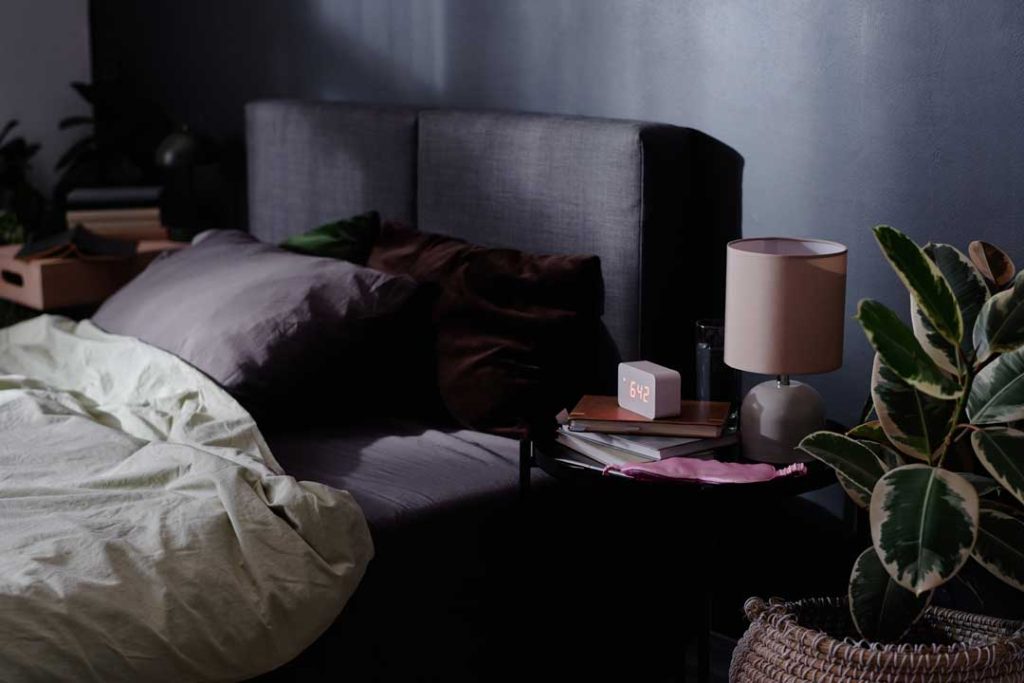 A dark and quiet bedroom setting with blackout curtains, a white noise machine, and comfortable bedding, illustrating an ideal sleep environment.
