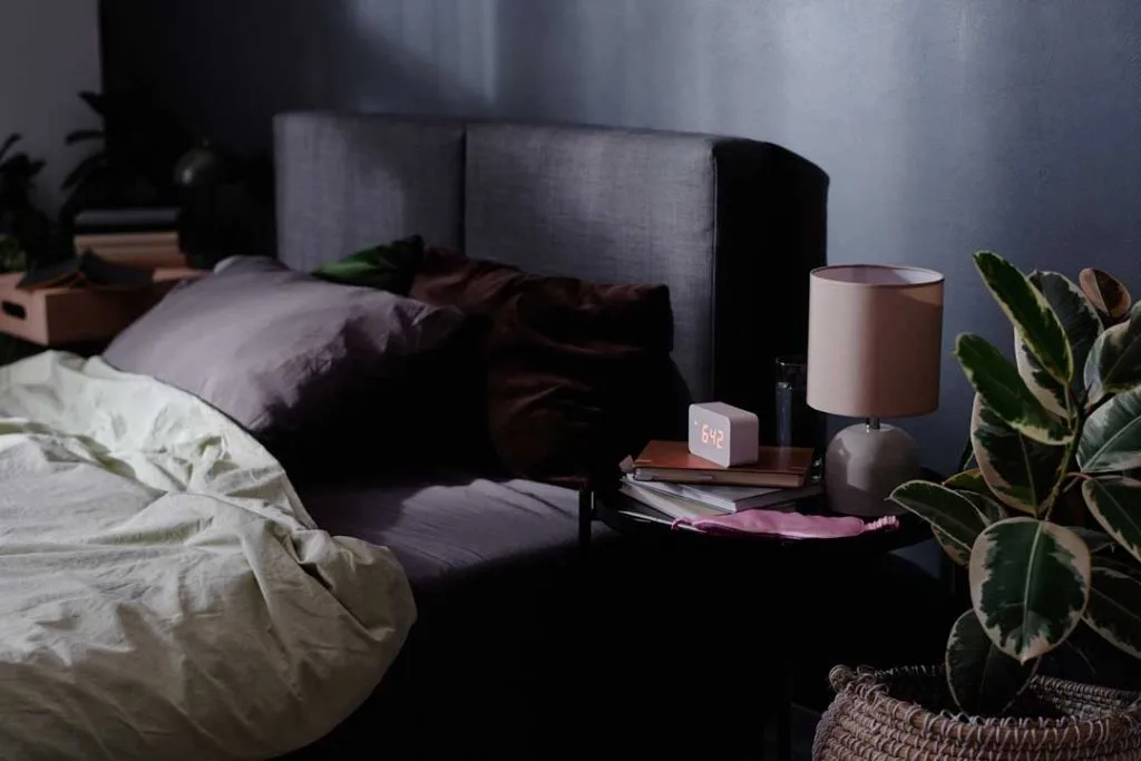 A dark and quiet bedroom setting with blackout curtains, a white noise machine, and comfortable bedding, illustrating an ideal sleep environment.