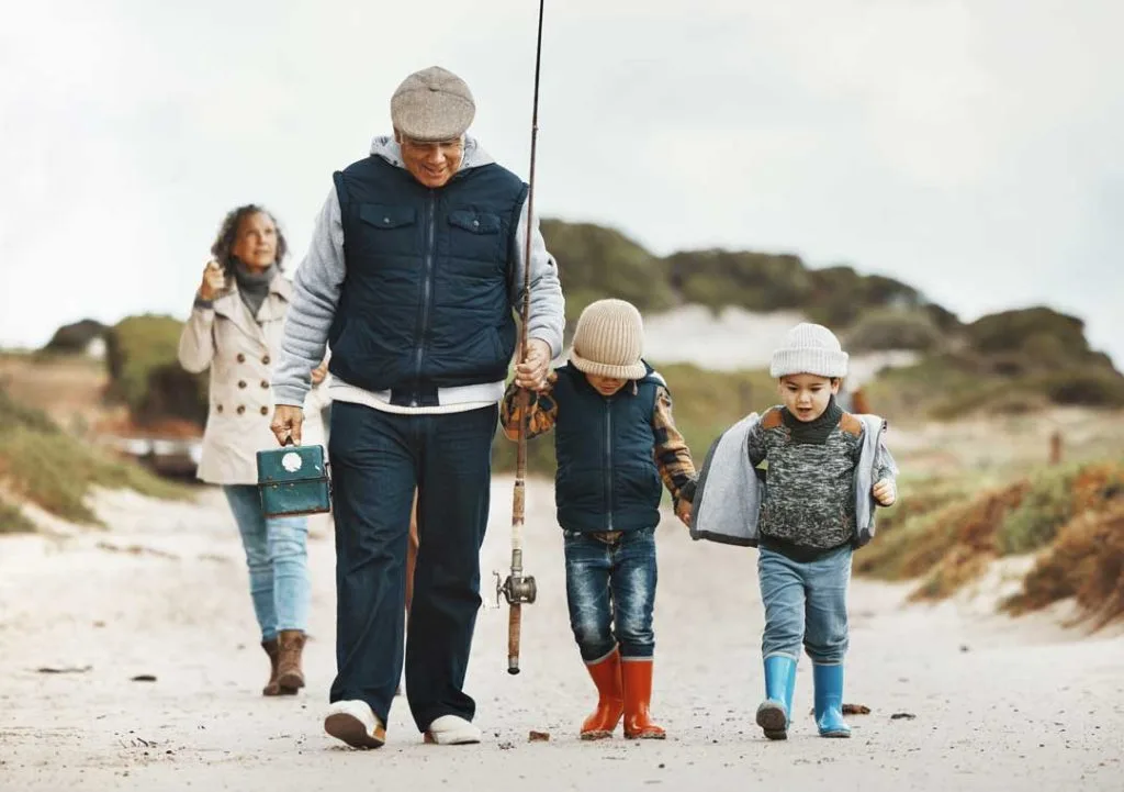 A family dressed in layers, including quick-dry shirts and hats, enjoying a fishing trip by the water, showcasing practical clothing for various weather conditions.