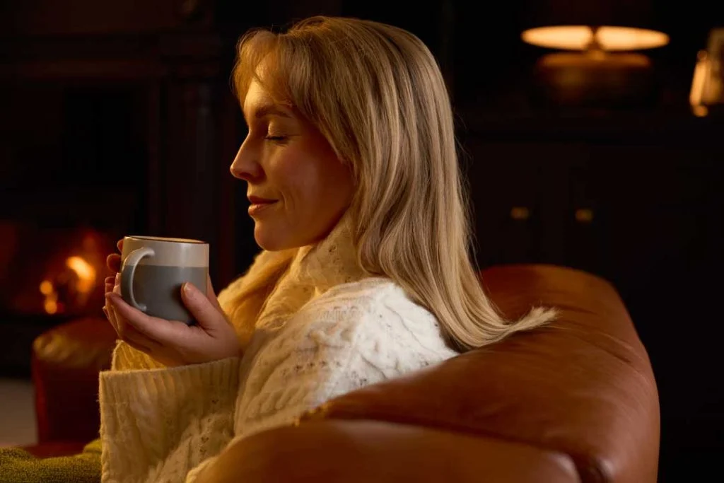 A person peacefully sipping herbal tea in the evening, highlighting sleep-friendly food and drink choices
