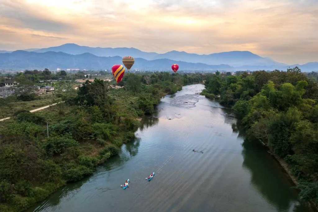 Hot air balloons floating over lush fields and rivers