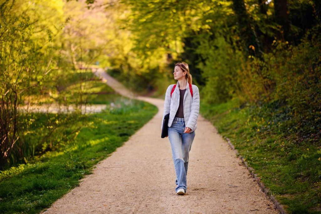 A person enjoying a calm morning walk outdoors, illustrating the benefits of early exercise for better sleep
