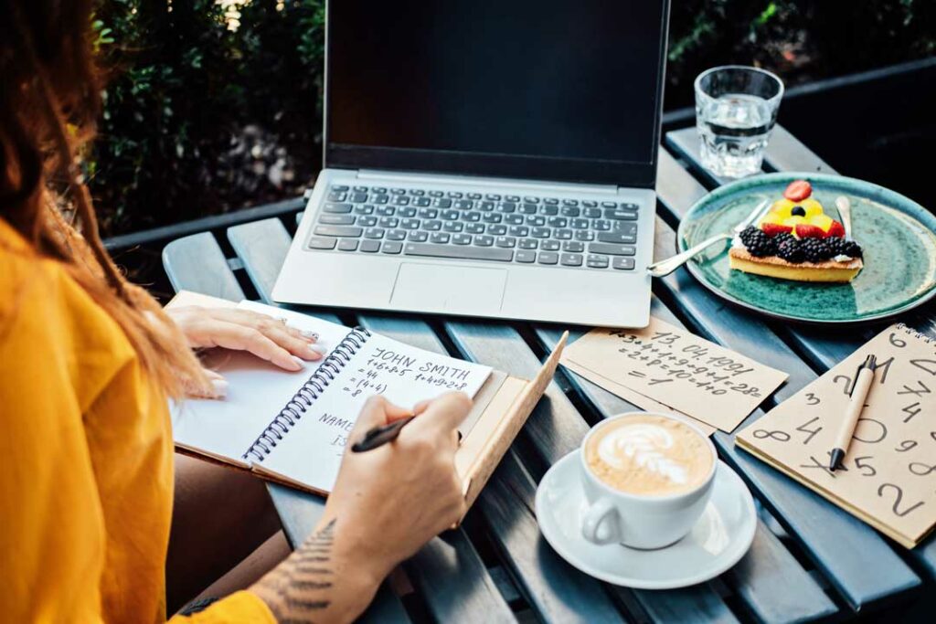 Woman typing on a laptop with planner and coffee