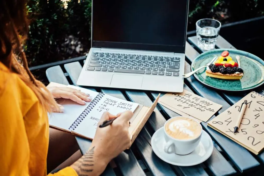 Woman typing on a laptop with planner and coffee
