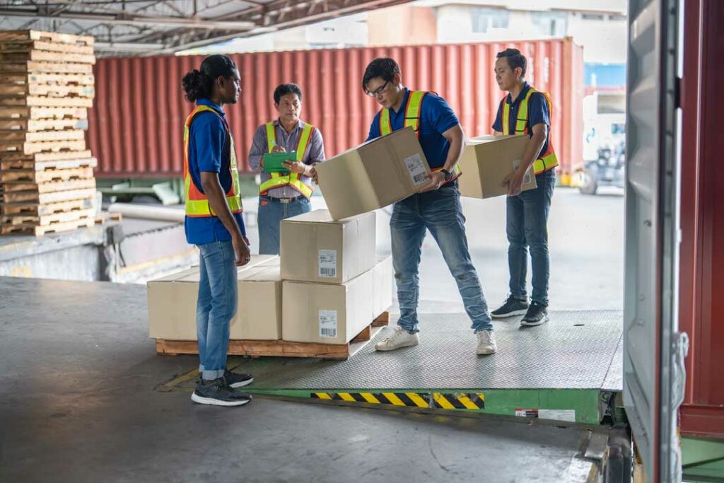 Workers transferring palletized goods from truck to truck