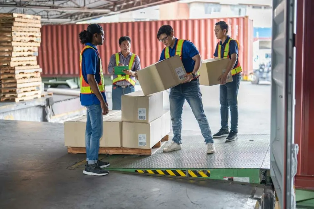 Workers transferring palletized goods from truck to truck