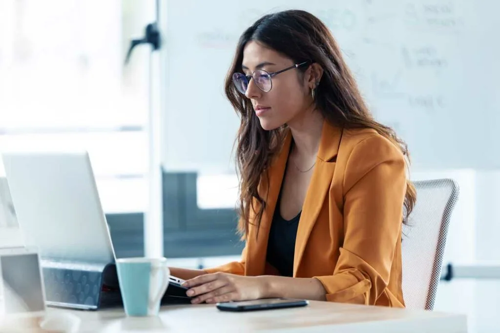 Woman working on a laptop, showing signs of eye strain