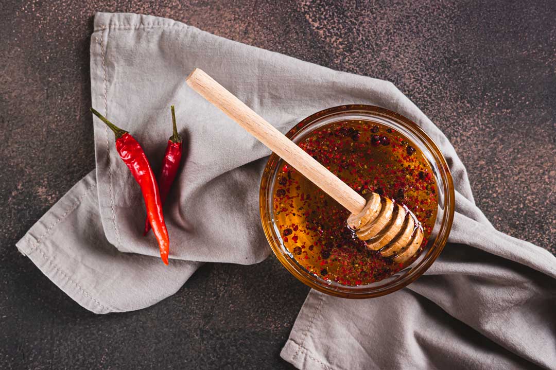 Hot honey sauce bottle with chili peppers and honey dipper