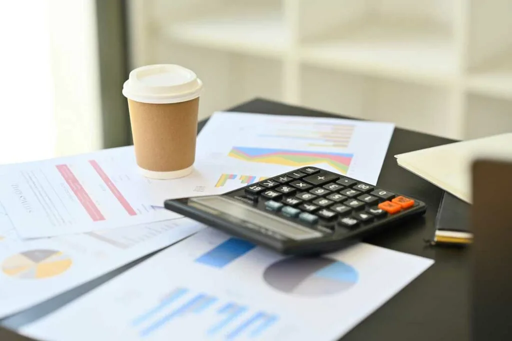 A coffee cup next to a calculator and bills