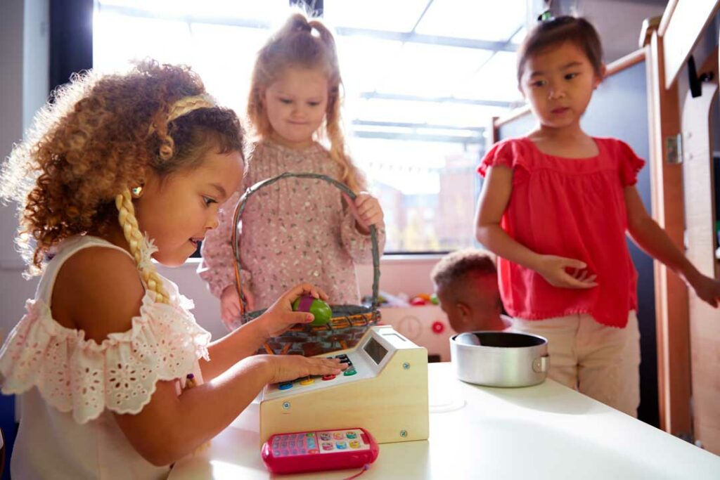 Preschooler role-playing in a pretend shop using play money