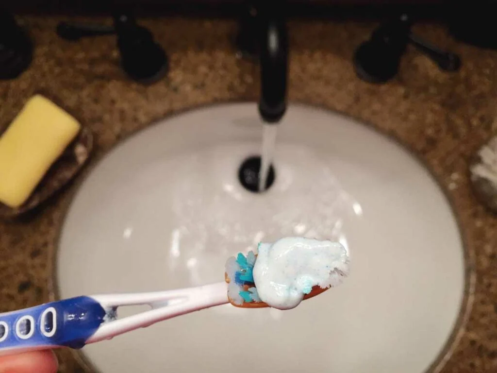 Close-up of toothbrush and floss on a clean sink
