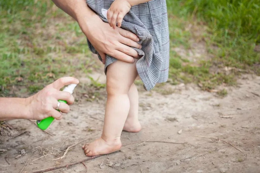 Parent applying mosquito repellent to child’s arm outdoors
