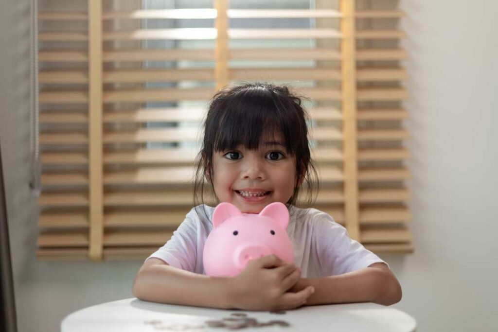 Preschooler learning about saving money with coins and piggy bank