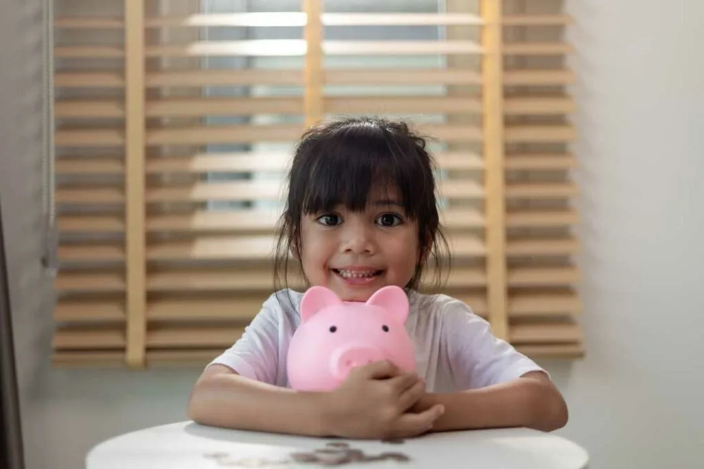 Preschooler learning about saving money with coins and piggy bank
