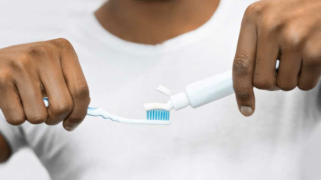 Person brushing teeth with fluoride toothpaste