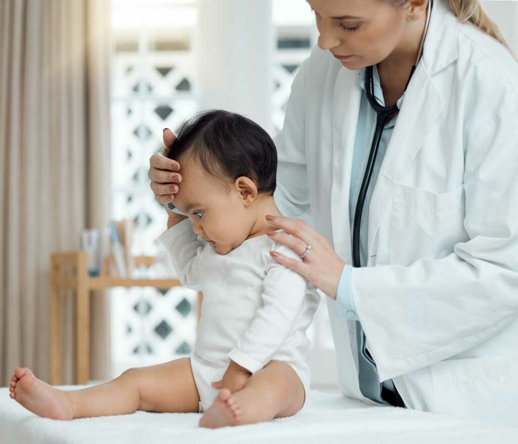 ediatrician gently checking a baby’s vitals or head while parent looks on