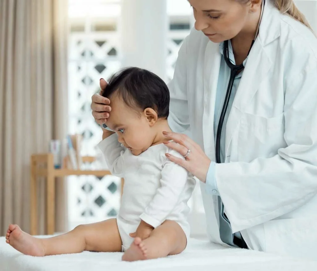 ediatrician gently checking a baby’s vitals or head while parent looks on