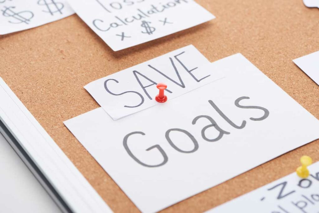 Close-up of a sticky note with small goal written (like ‘save $5 a week’)