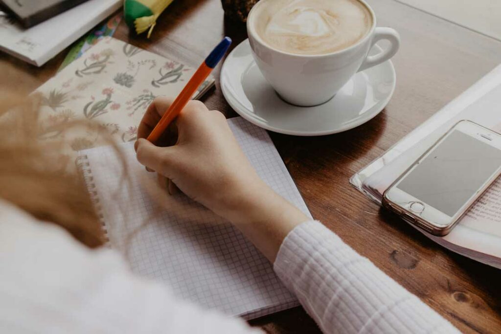 Person journaling with a cup of coffee, planning budget