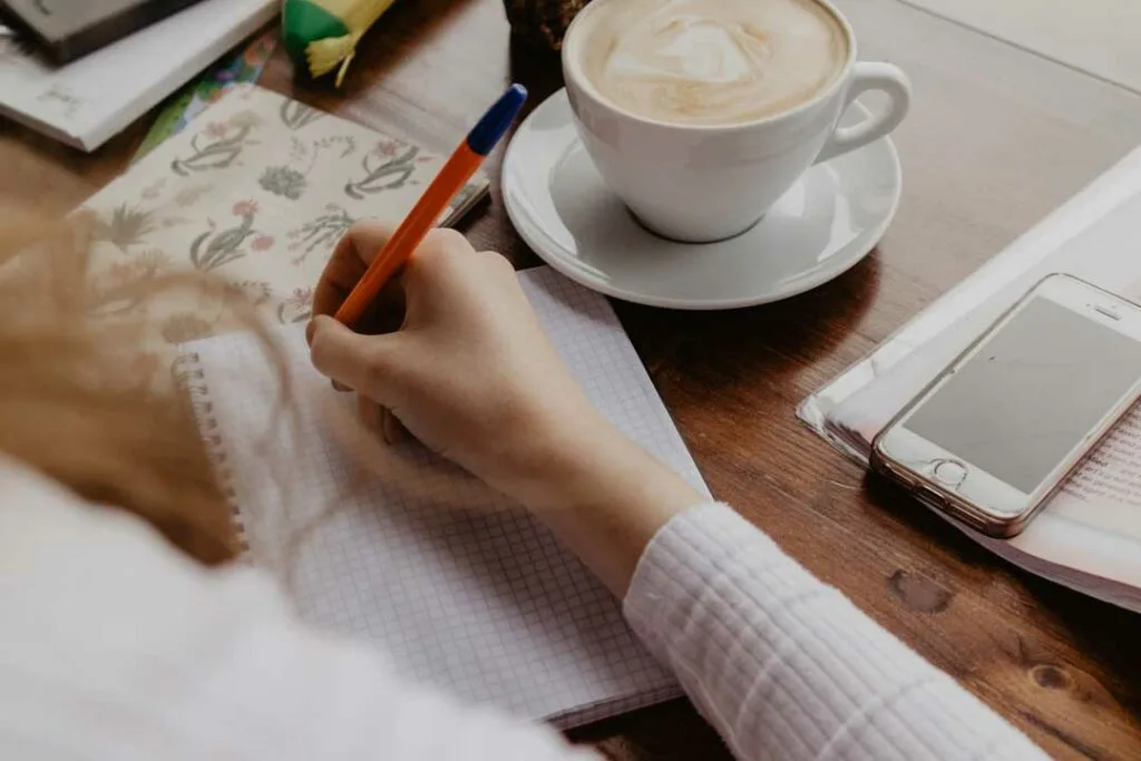 Person journaling with a cup of coffee, planning budget