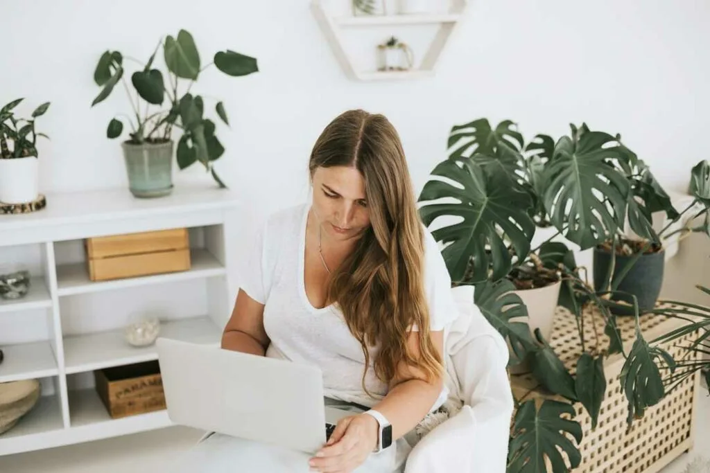 mom at her laptop in a bright room with plants